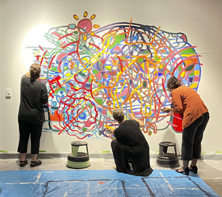 Visitors painting a gallery wall together